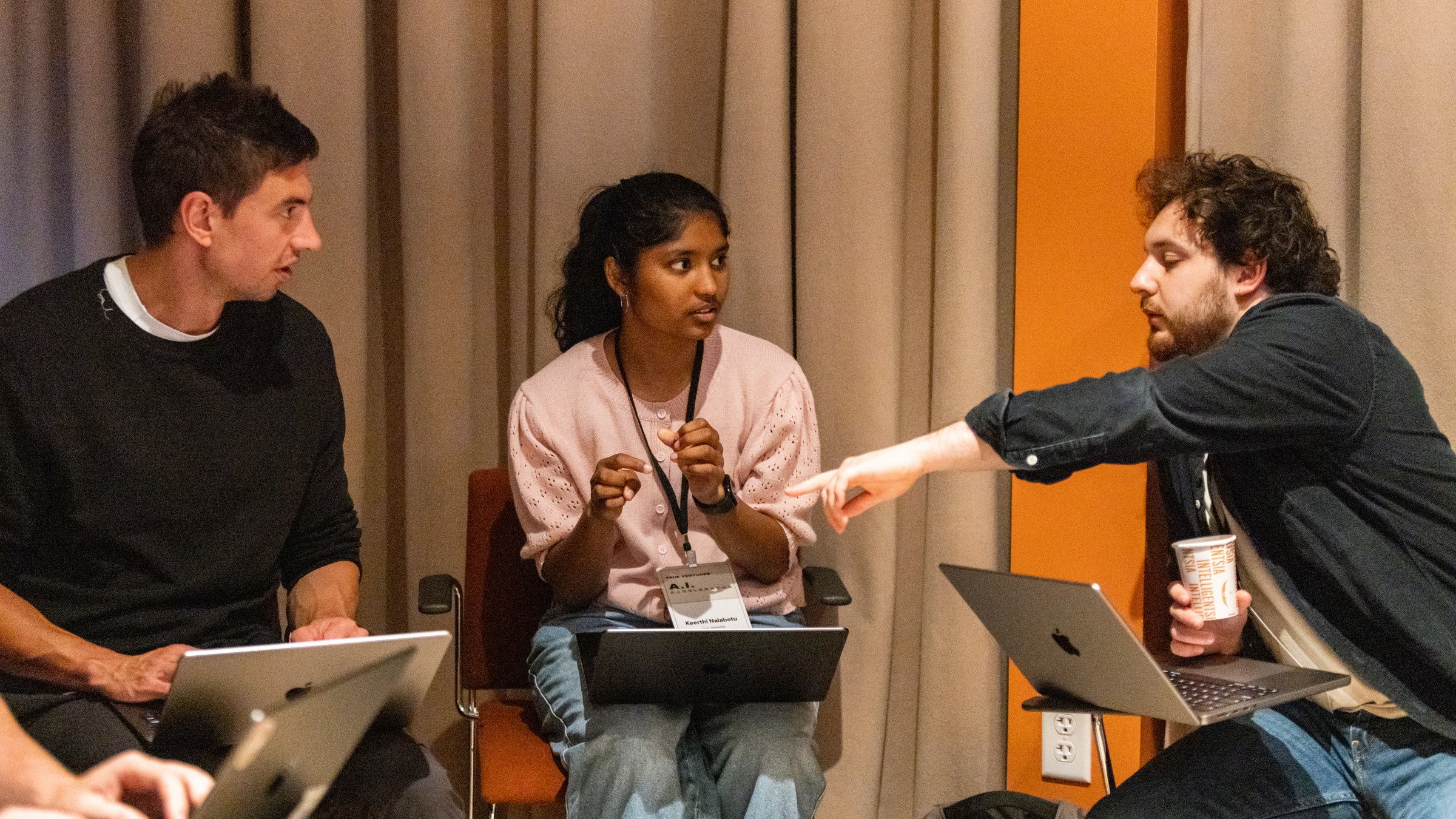Mike Montano and Keerthi Nalabotu working on laptops with a fellow builder at a True Ventures AI event